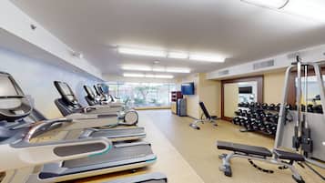 Un gimnasio con cintas de correr, mancuernas y máquinas de pesas.