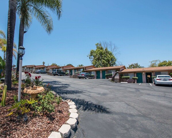 A row of motel buildings with a paved parking area and a landscaped garden with cacti and shrubs. - Rodeway Inn Fallbrook Downtown (Fallbrook)