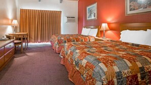 Habitación de hotel con dos camas, un escritorio, una silla y una ventana con cortinas.