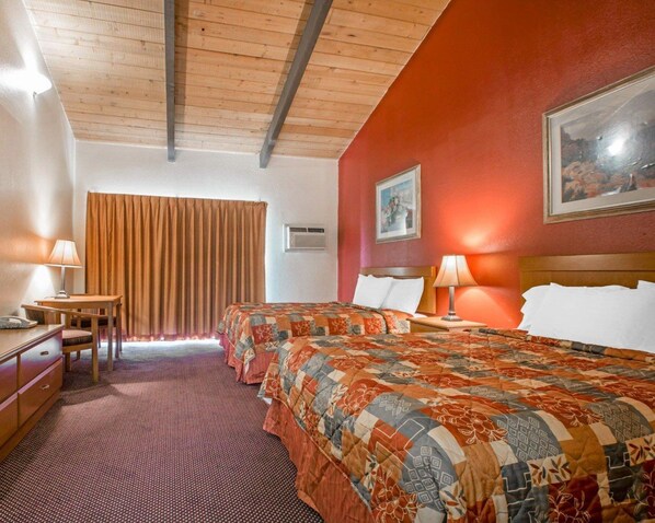A hotel room with two beds, a desk, a chair, and a window with curtains. - Rodeway Inn Fallbrook Downtown (Fallbrook)