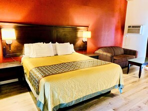 A hotel room with a large bed, two bedside lamps, a striped armchair, and a small table.