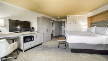 Ein Hotelzimmer mit Bett, Schreibtisch mit Flachbildfernseher, Mikrowelle, Sessel und Kleiderschrank.