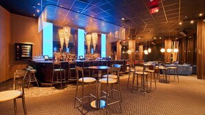 A bar area with stools, a bar counter, and a chandelier. - Holiday Inn Mobile-Dwtn/Hist. District by IHG (Mobile)