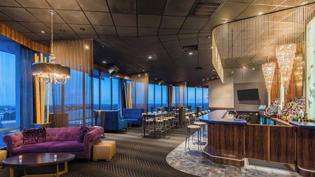 A modern lounge area with a bar, seating, and large windows offering a view. - Holiday Inn Mobile-Dwtn/Hist. District by IHG (Mobile)
