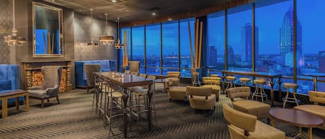A modern lounge area with a large window overlooking a cityscape at dusk.