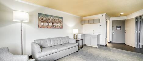 Un salón moderno con un sofá gris, una lámpara de pie y un cuadro en la pared.