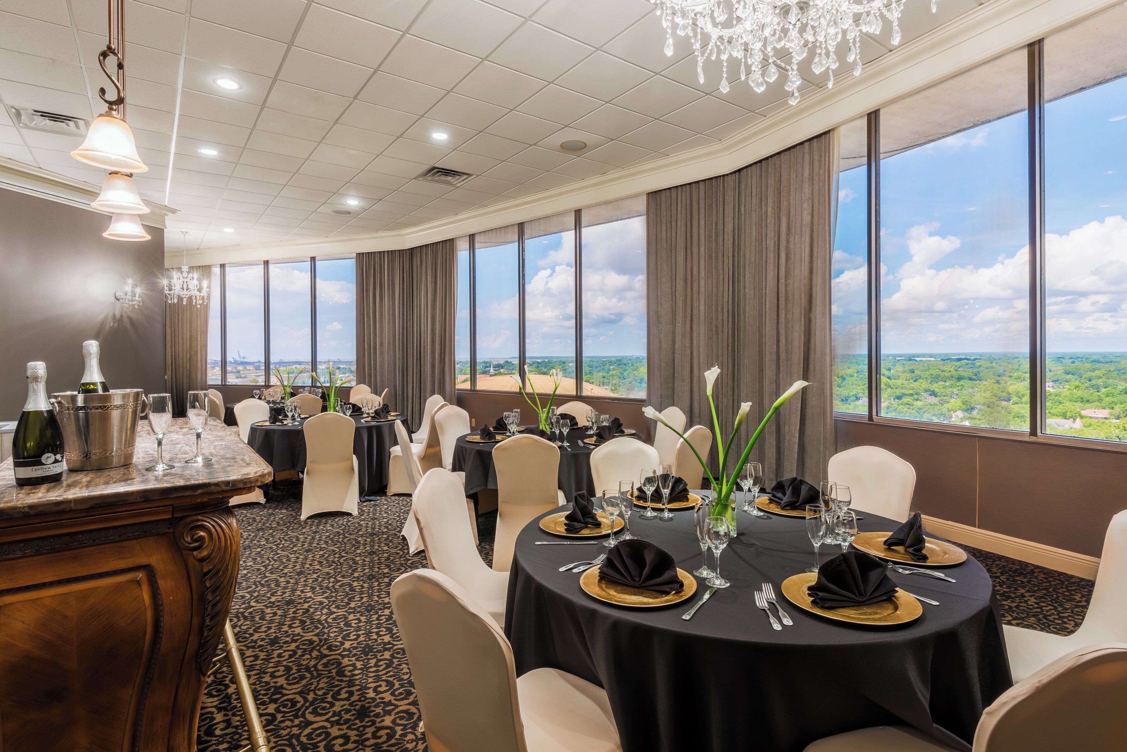 A dining area with round tables, chairs, and a view of the landscape through large windows.