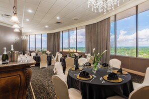 Un espace repas avec des tables rondes, des chaises et une vue sur le paysage grâce à de grandes fenêtres.