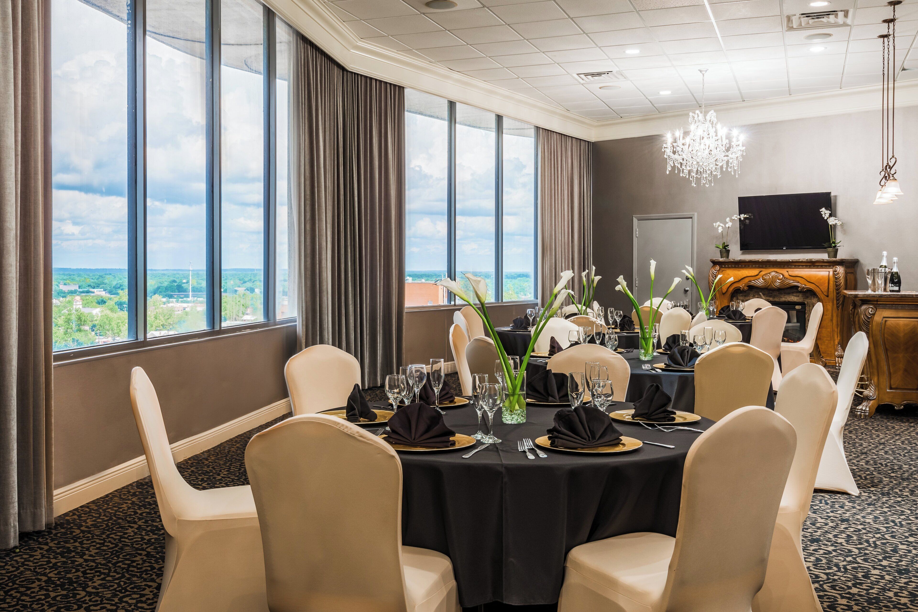 A conference room with a table set for a formal event, large windows, and a fireplace.