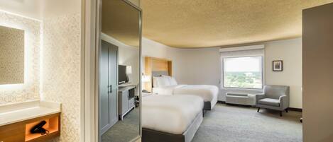 A hotel room with a bed, a desk, a chair, and a window.