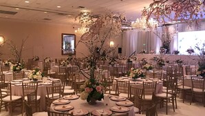 A banquet hall with round tables, wooden chairs, and floral centerpieces. - Holiday Inn Mobile-Dwtn/Hist. District by IHG (Mobile)