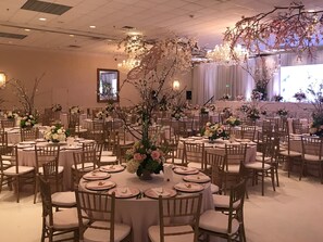 A banquet hall with round tables, wooden chairs, and floral centerpieces. - Holiday Inn Mobile-Dwtn/Hist. District by IHG (Mobile)