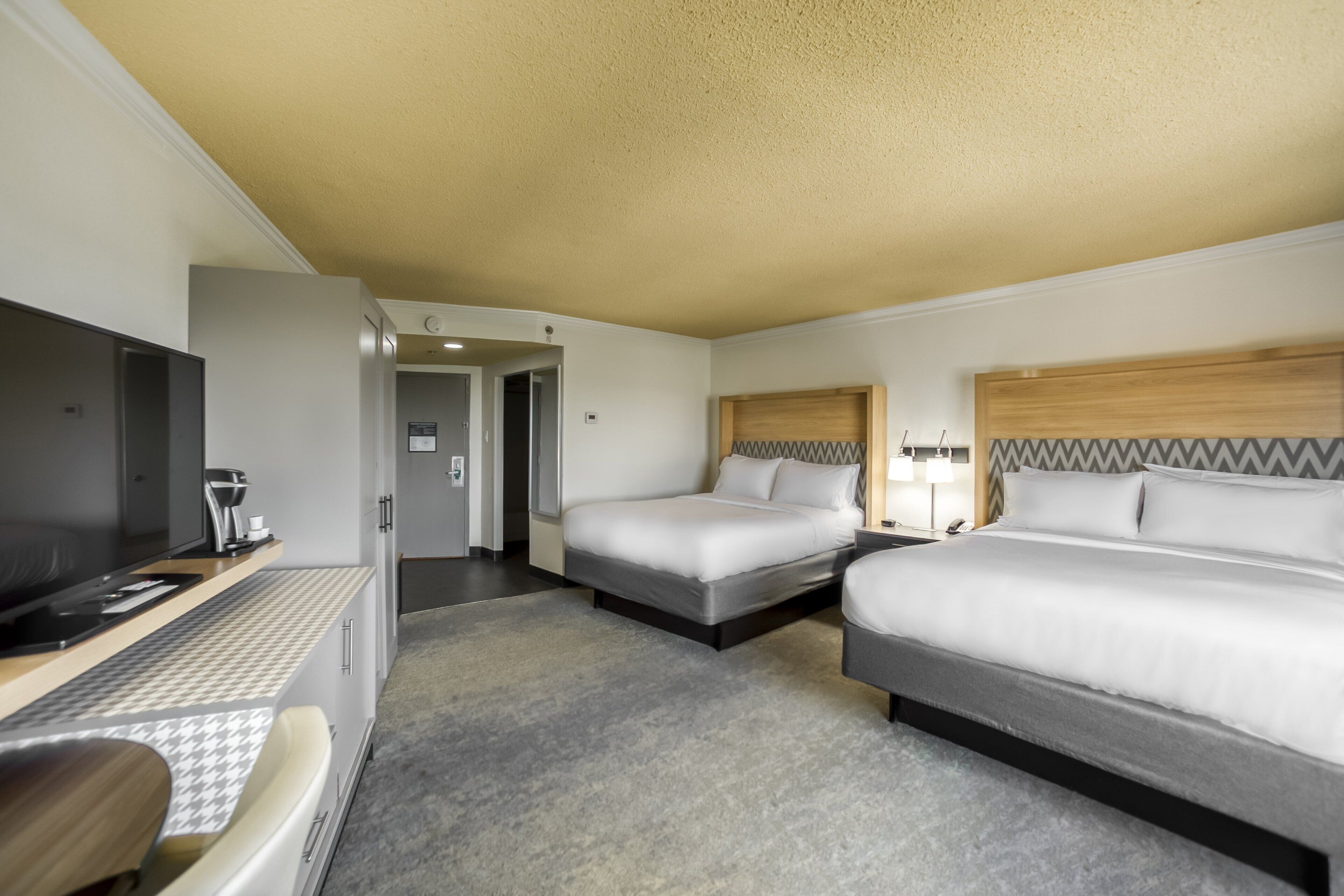 Een hotelkamer met een bed, een bureau met een computer, een stoel en een televisie.