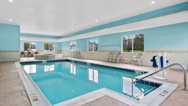 A swimming pool with clear water, surrounded by white chairs and a sun lounger. - Best Western Paradise Inn (Savoy)
