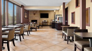 A dining area with multiple tables and chairs, a flat-screen TV mounted on the wall, and a fireplace. - Best Western Paradise Inn (Savoy)