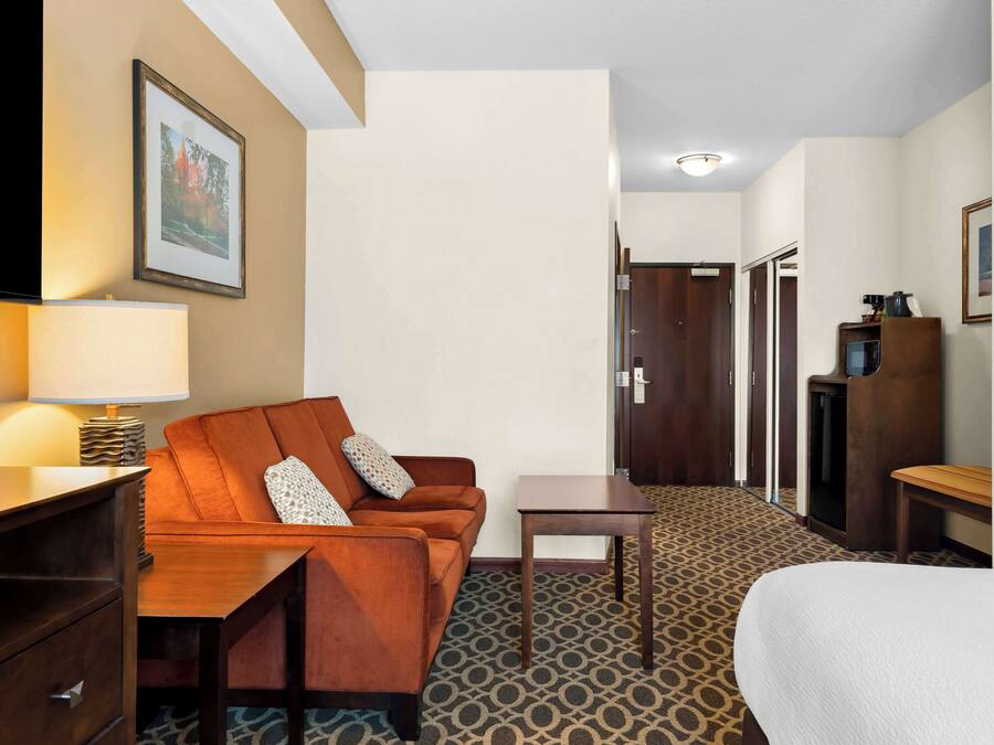 A hotel room with a sofa, a small table, a TV, and a bed.