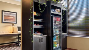 A compact kitchenette with a refrigerator, shelves, and a window with blinds. - Best Western Paradise Inn (Savoy)