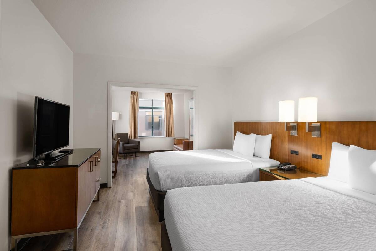 Een hotelkamer met twee bedden, een televisie, een bureau en een raam met gordijnen.