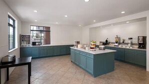 Une cuisine spacieuse avec des meubles de couleur turquoise, un îlot central et un coin repas comprenant une table et des chaises.