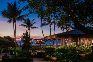 A beachfront restaurant with outdoor seating, palm trees, and a view of the sea. - OUTRIGGER Kaanapali Beach Resort (Lahaina)