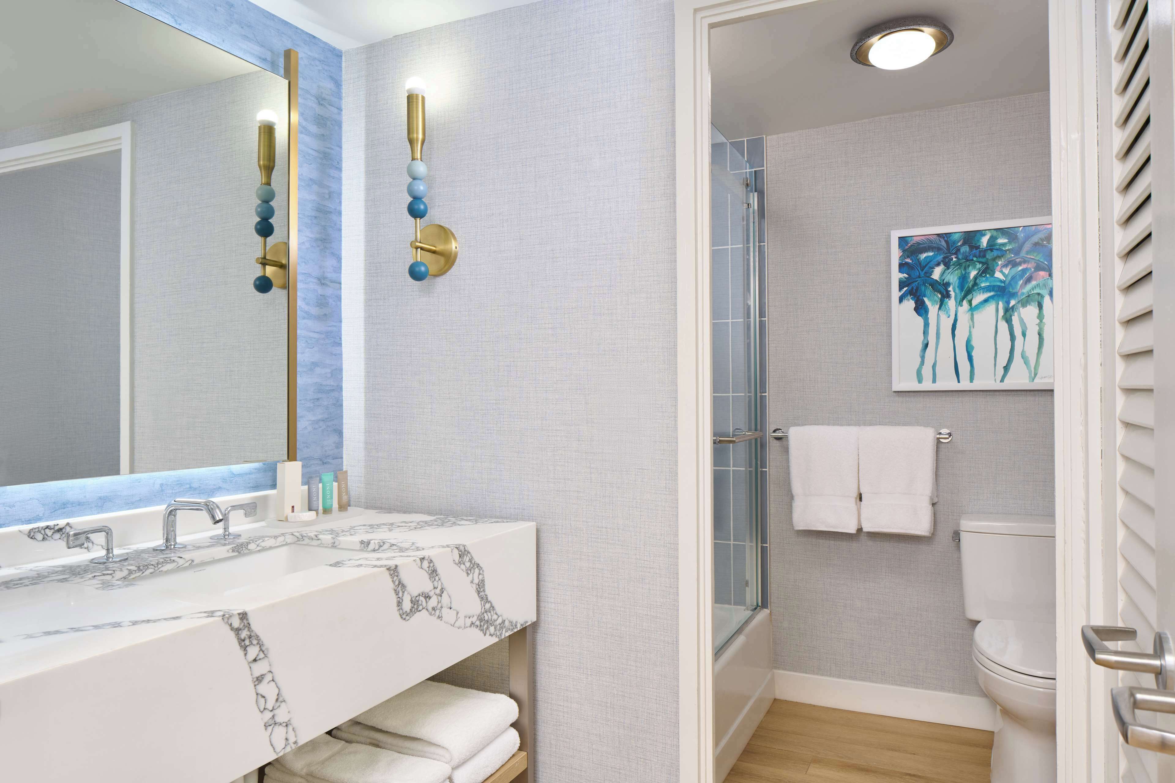 Un baño con lavamanos de mármol, cabina de ducha de vidrio y un inodoro.