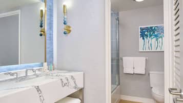 Un baño con lavamanos de mármol, cabina de ducha de vidrio y un inodoro.