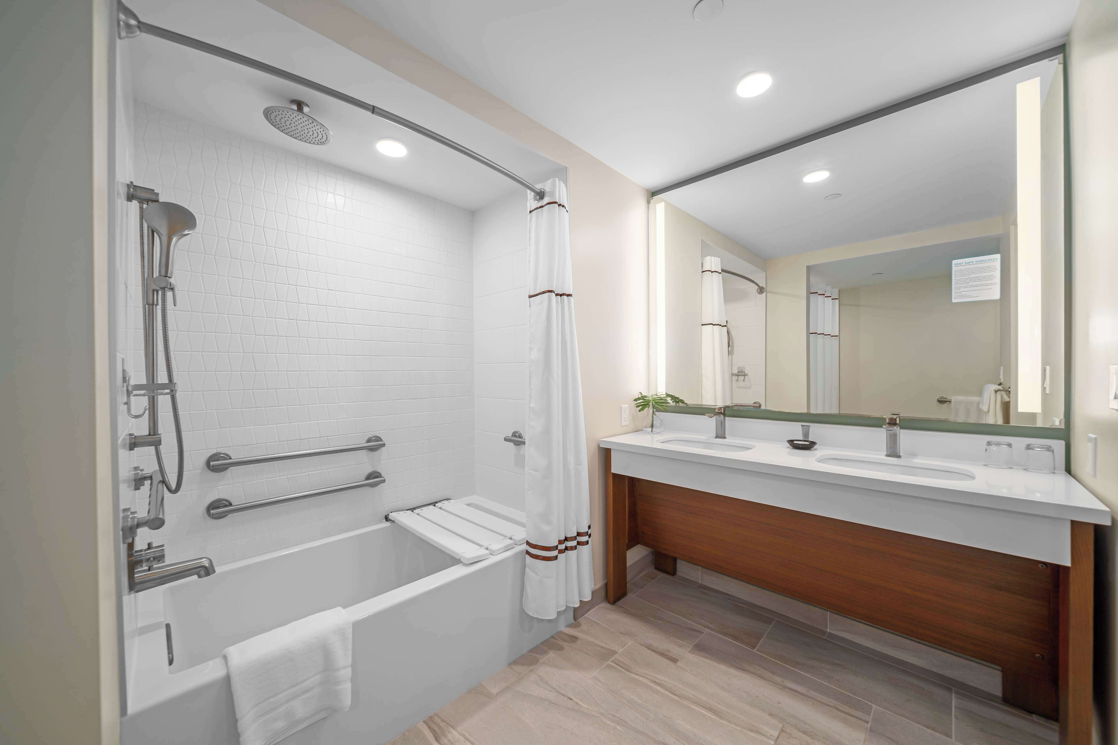 A modern bathroom with a bathtub, shower, and vanity with a mirror.
