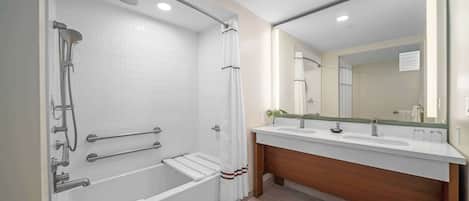 A modern bathroom with a bathtub, shower, and vanity with a mirror.