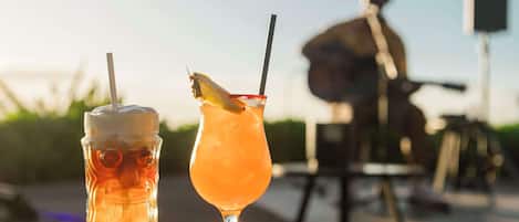 Two drinks on a table with a person in the background.