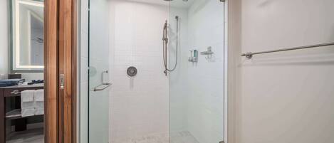 A glass-enclosed shower with a handheld showerhead and a wall-mounted faucet.
