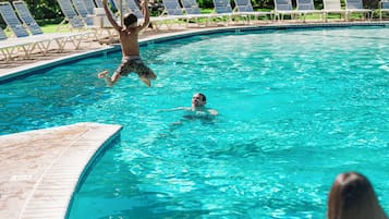 Una piscina al aire libre, sillones reclinables de piscina