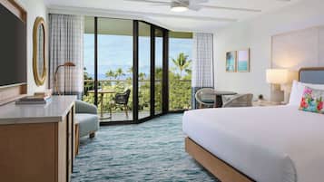 Habitación de hotel con cama, escritorio, silla, balcón con vistas y ventilador de techo.