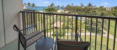 A balcony with a view of the ocean and palm trees.