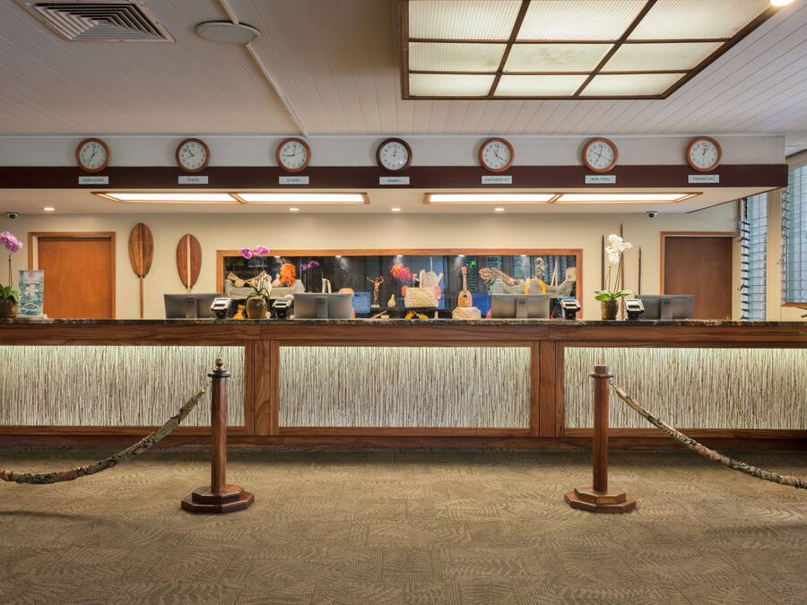 A reception desk with clocks, a wooden counter, and a large window.