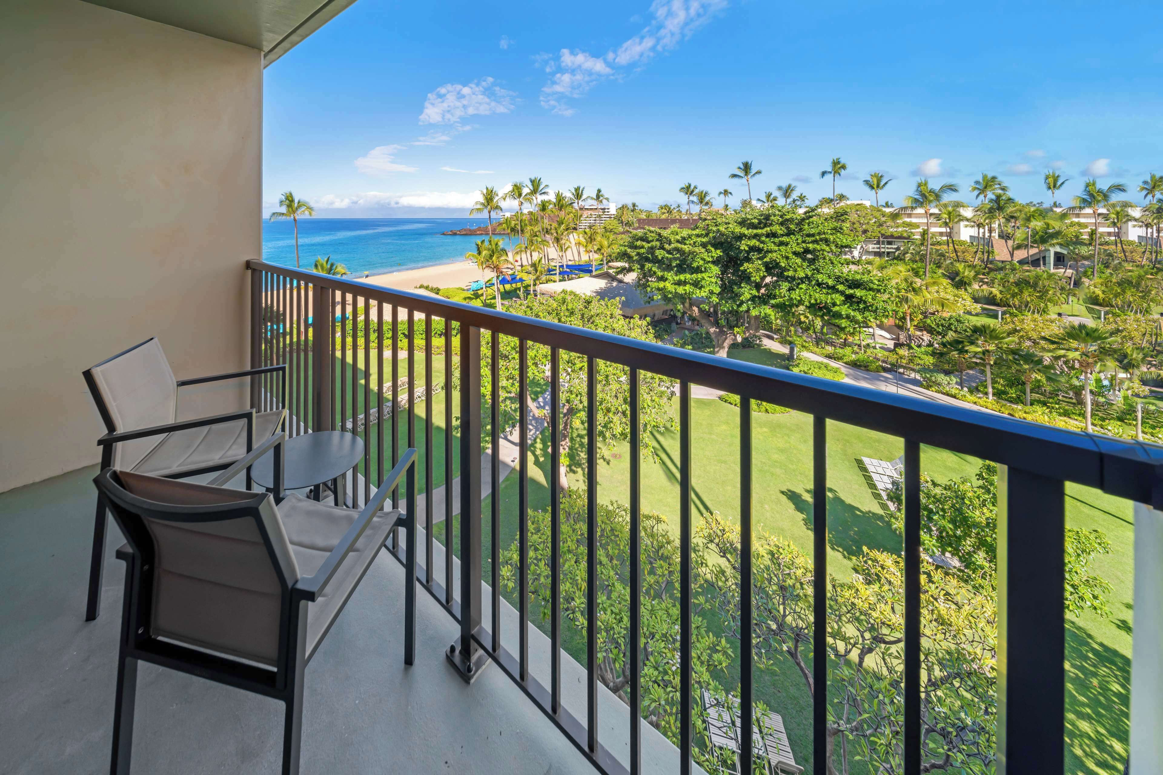 A balcony with a view of a beach, palm trees, and a golf course.