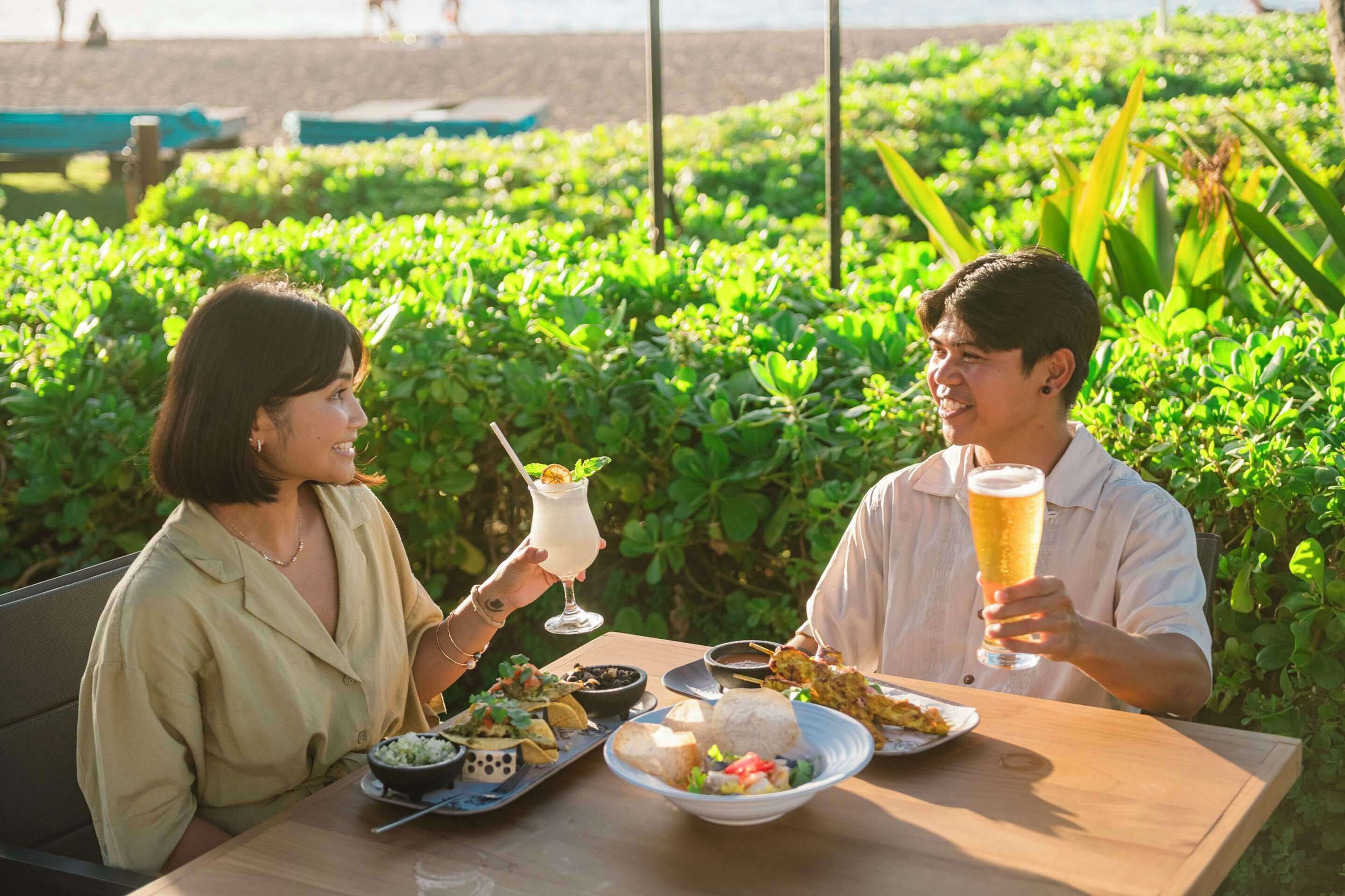 Two people dining outdoors with a table set with food and drinks.