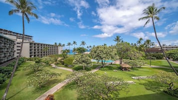 Un hotel con piscina, palmeras y un césped cuidado.