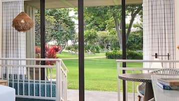A room with a large sliding glass door, a wicker chair, a small table, and a hanging light fixture.