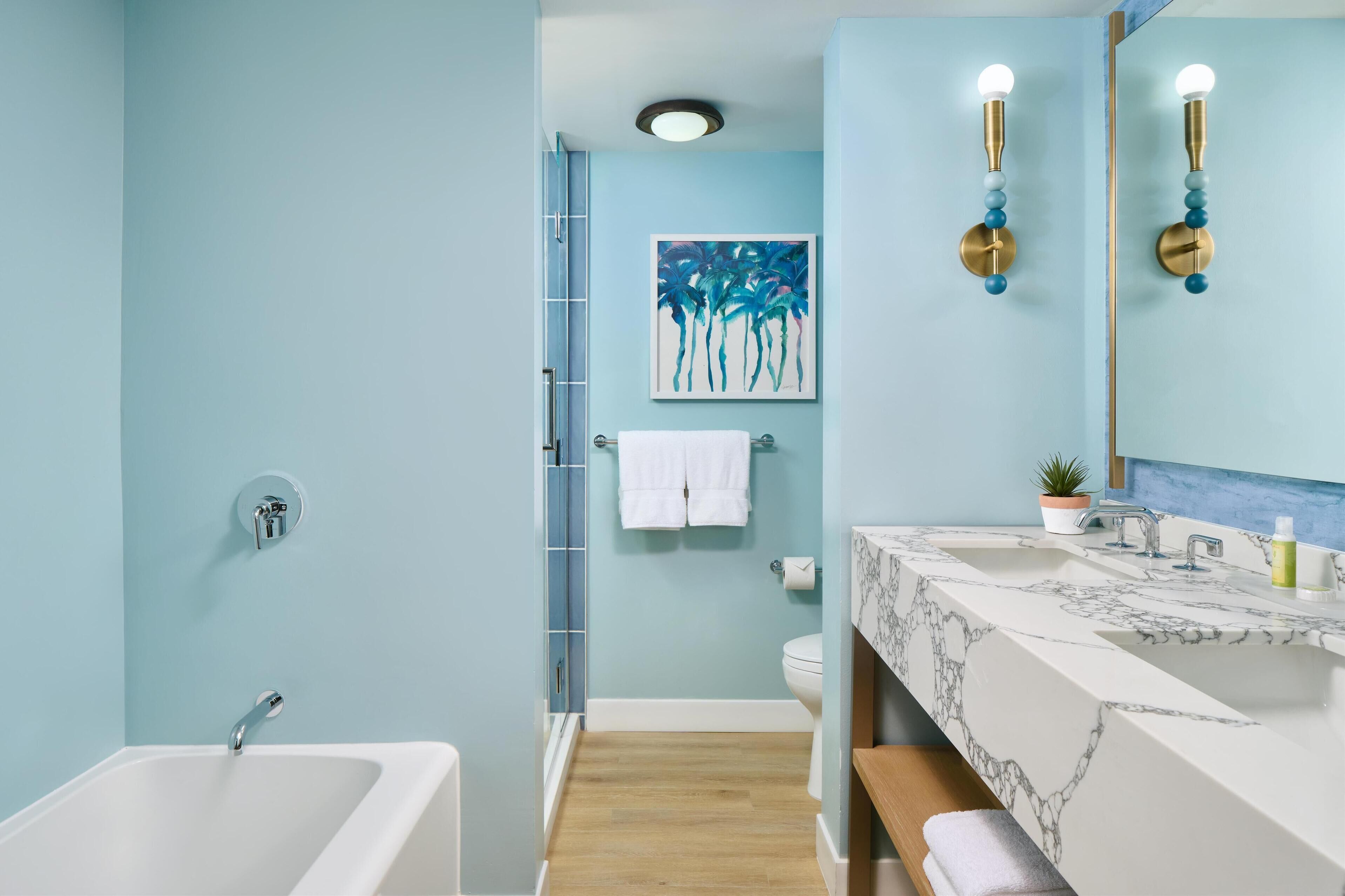 A bathroom with a bathtub, a sink with a marble countertop, a shower, and a towel rack.