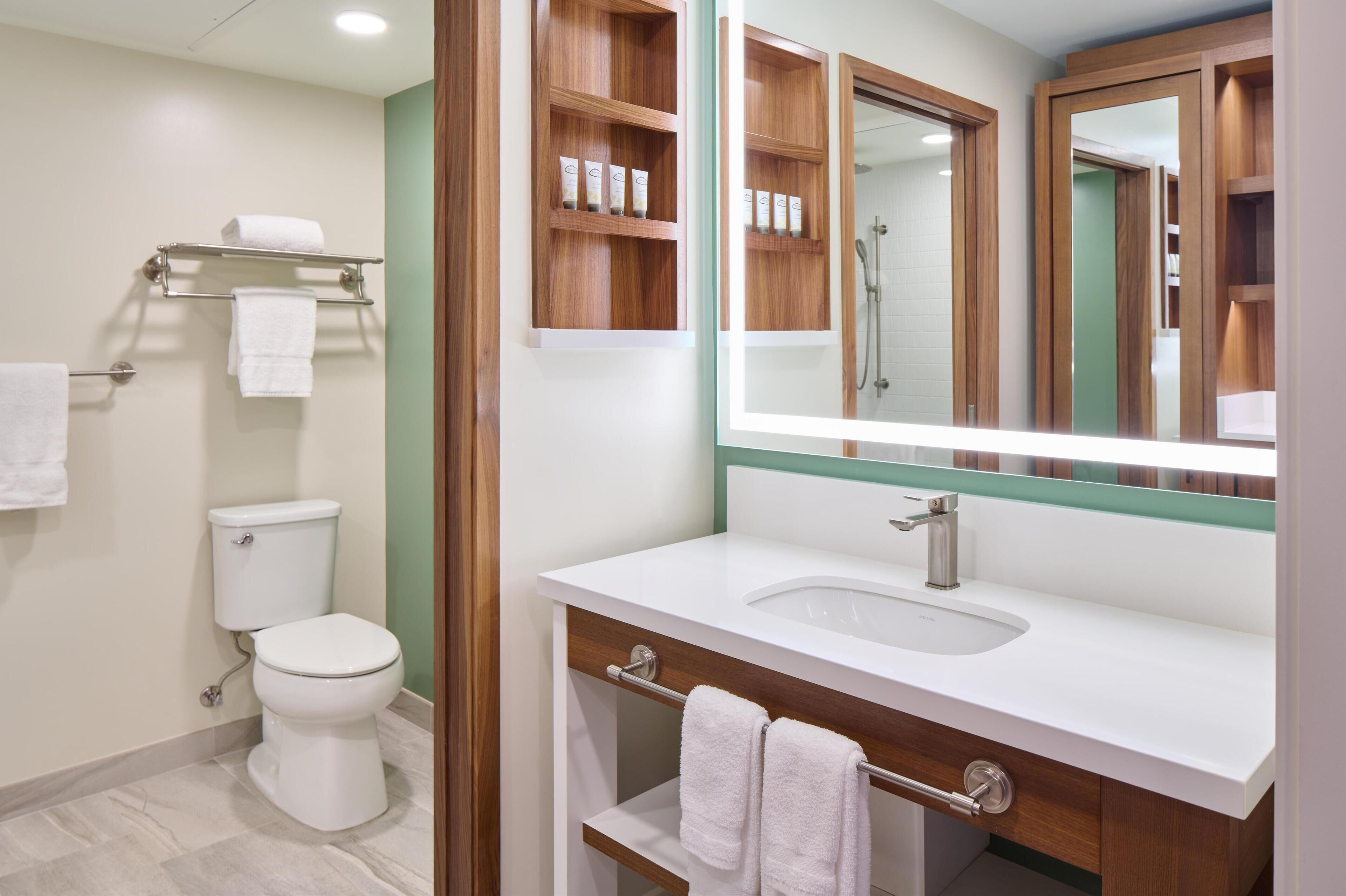 A bathroom with a toilet, a sink, a mirror, and a towel rack.