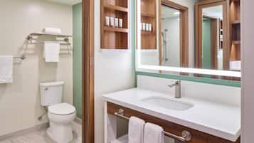 Un baño con inodoro, lavabo, espejo y toallero.