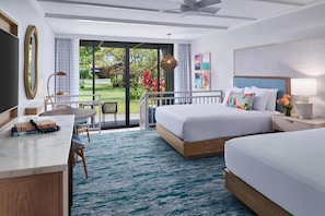 A hotel room with a bed, bedside table, desk, chair, and a view of a garden through large windows.