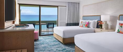 Une chambre d’hôtel avec deux lits, une télévision, un bureau, une chaise et un balcon donnant sur la mer.