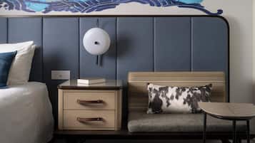 Une chambre d’hôtel comprenant un lit, une table de chevet, une lampe, une commode et une petite table avec une chaise.