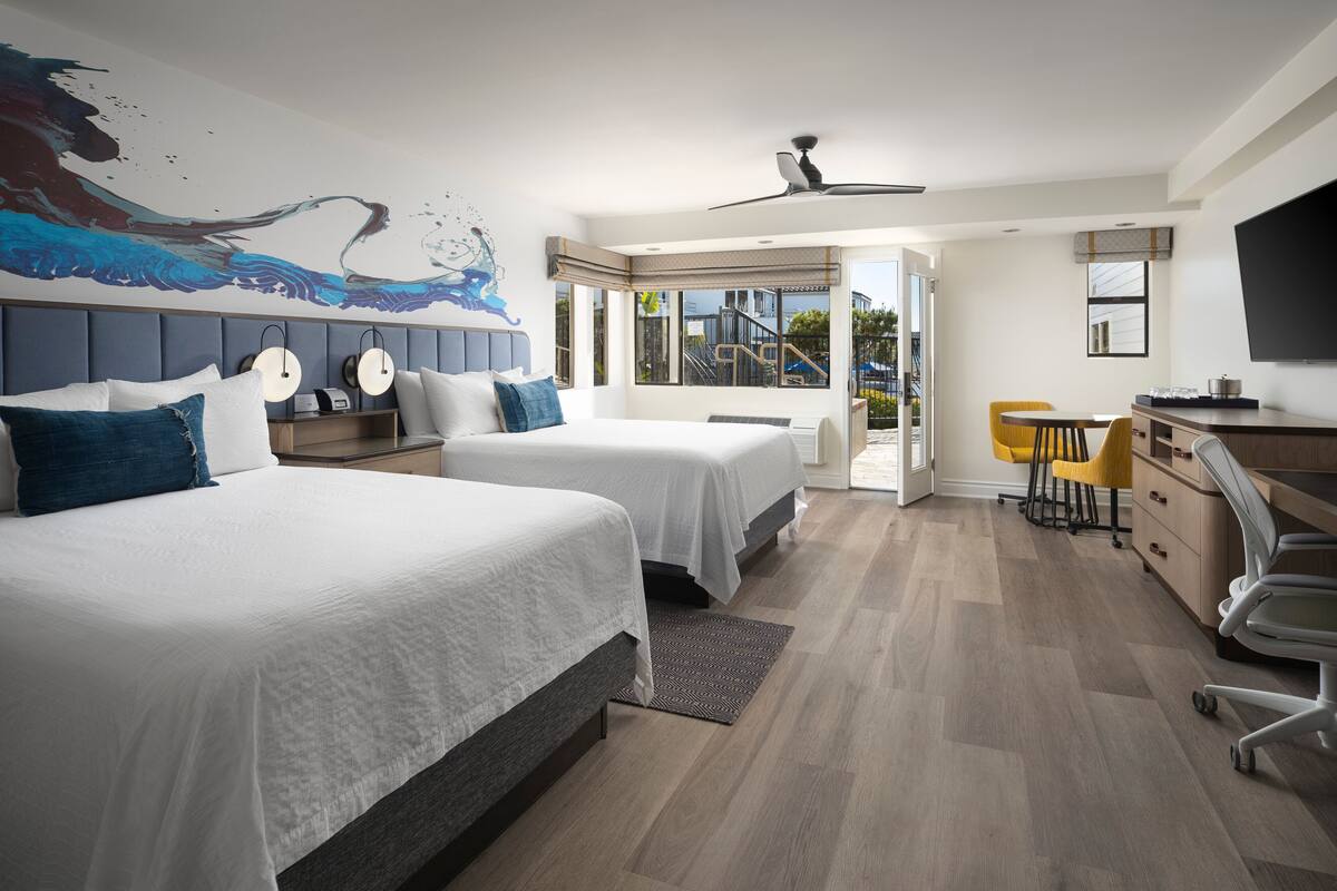 Een moderne hotelkamer met twee bedden, een zithoek en uitzicht op buiten.
