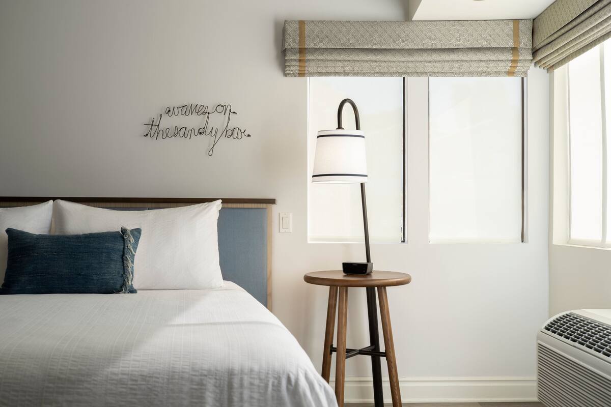 Een netjes ingerichte hotelkamer met een bed, een bedlampje en een decoratief wandobject.