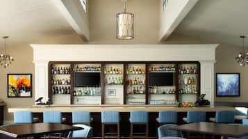 Zona de bar con diversas opciones de asientos y una variedad de botellas de licor en estantes.
