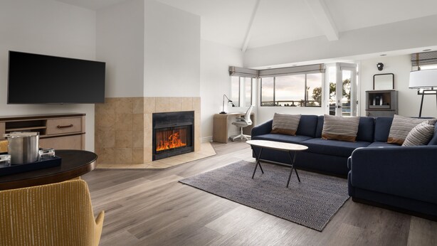 Un salon moderne avec une cheminée, un canapé, une table basse et un téléviseur.