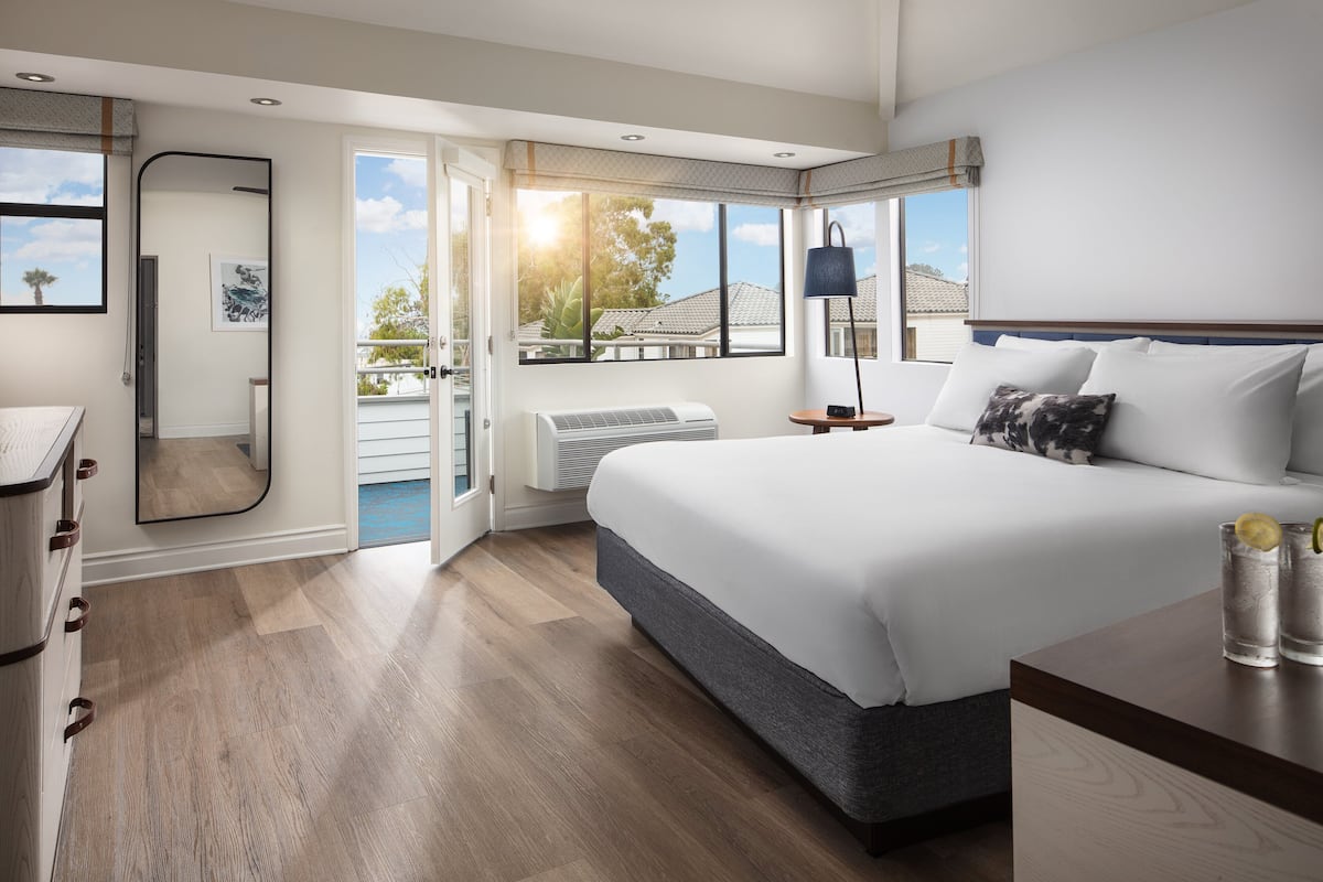 Une chambre moderne dotée d’un grand lit, d’un dressing, d’une salle de bain et d’un balcon offrant une vue sur le quartier.