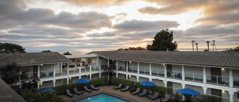 Un hotel con piscina, sillas de descanso y vistas al atardecer.